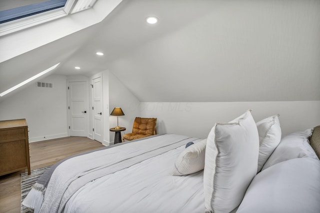 bedroom with visible vents, wood finished floors, vaulted ceiling with skylight, and recessed lighting
