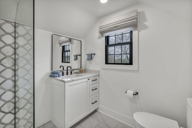 bathroom with baseboards, toilet, vanity, and vaulted ceiling