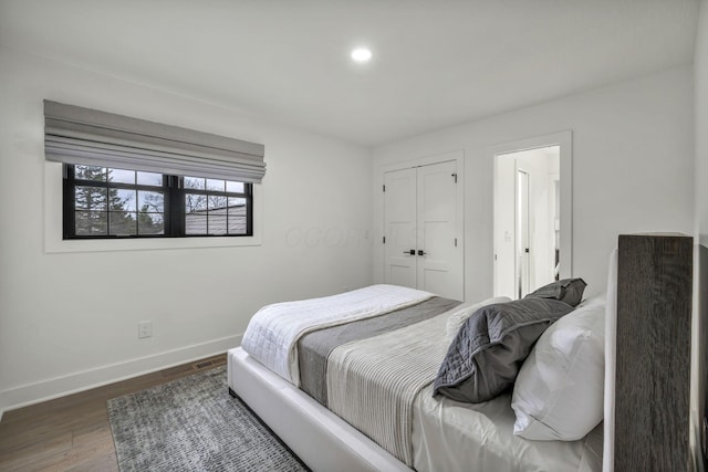 bedroom with wood finished floors, a closet, recessed lighting, and baseboards