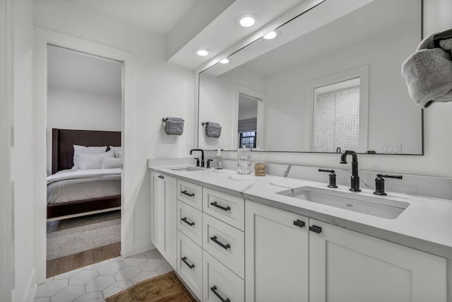 ensuite bathroom featuring double vanity, recessed lighting, tile patterned flooring, and a sink