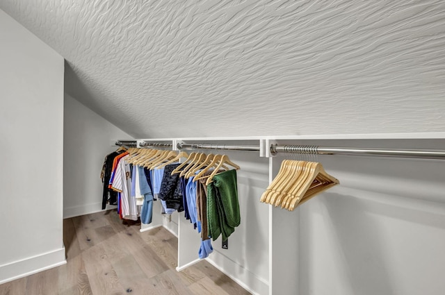 spacious closet featuring wood finished floors and vaulted ceiling