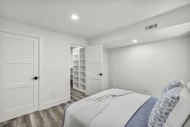 bedroom featuring wood finished floors, recessed lighting, visible vents, and a walk in closet