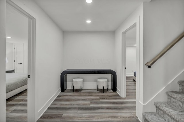 corridor featuring recessed lighting, stairway, wood finished floors, and baseboards