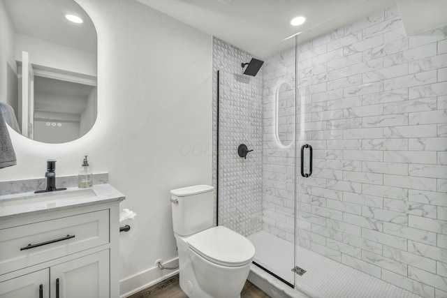 bathroom with toilet, a shower stall, wood finished floors, and vanity