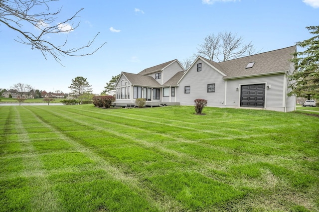 rear view of property featuring a yard, a sunroom, and roof with shingles