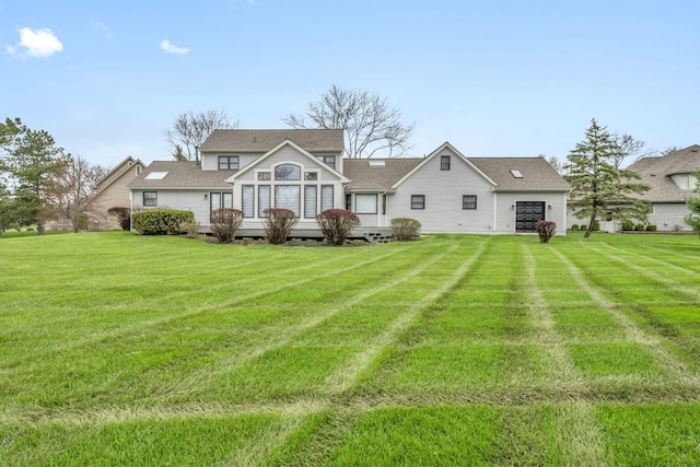 back of house featuring a lawn, roof with shingles, and a deck