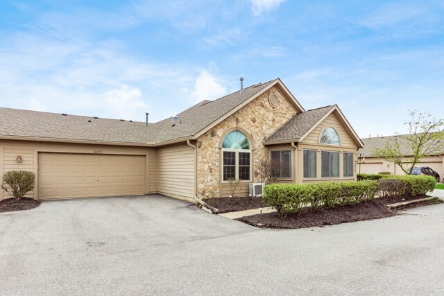 3673 Stoneway Pt, Powell, OH 43065 - ranch-style house with stone siding, asphalt driveway, an attached garage, and roof with shingles