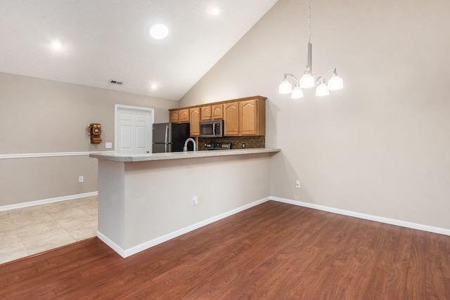 3673 Stoneway Pt, Powell, OH 43065 - kitchen featuring stainless steel appliances, a chandelier, a peninsula, light countertops, and light wood-style floors