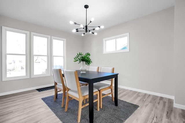 dining room featuring light wood-style flooring, an inviting chandelier, baseboards, and visible vents