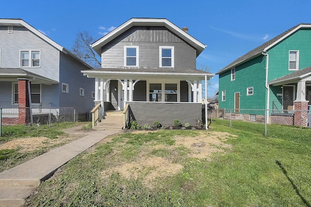 view of front facade with a porch, board and batten siding, fence, and a front lawn