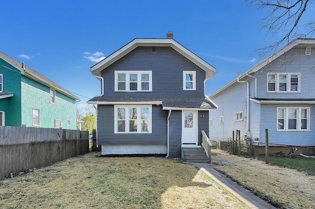 view of front of house with entry steps, a front yard, and fence