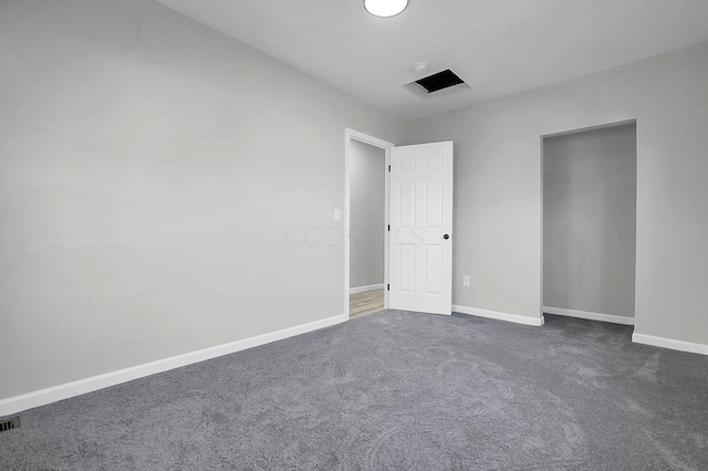 empty room featuring dark carpet, baseboards, and visible vents
