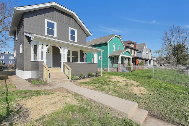 view of front of property featuring covered porch, a front yard, and fence