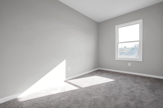 carpeted spare room featuring baseboards and lofted ceiling