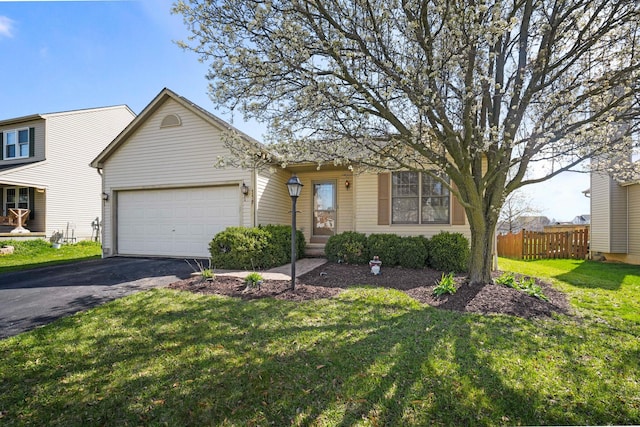view of front of house featuring a front yard, an attached garage, fence, and aphalt driveway