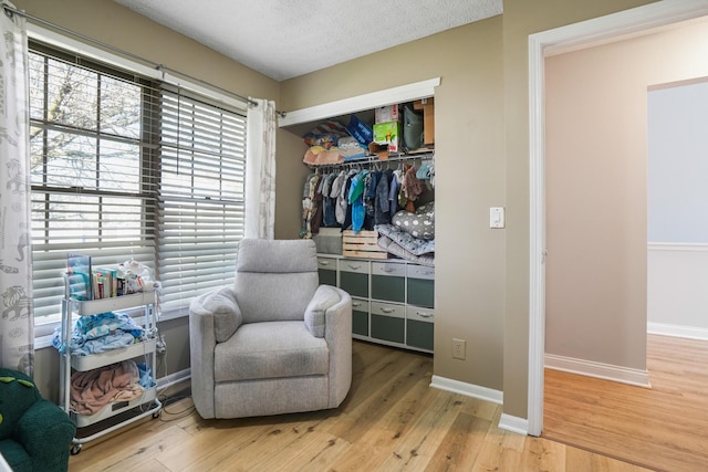 sitting room featuring baseboards, a textured ceiling, and wood finished floors