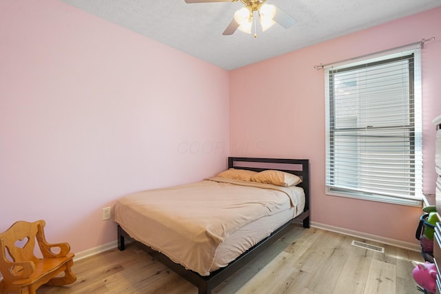 bedroom featuring baseboards, visible vents, light wood-type flooring, and multiple windows