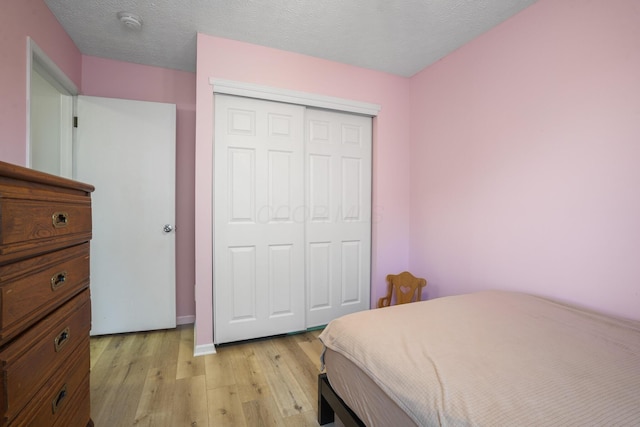 bedroom with light wood-style flooring, a closet, and a textured ceiling