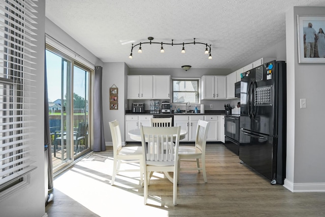 dining area featuring light wood finished floors, baseboards, a textured ceiling, and a healthy amount of sunlight