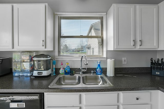 kitchen featuring a sink, white cabinets, dark countertops, and dishwashing machine