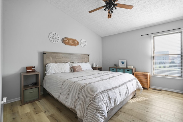 bedroom featuring baseboards, vaulted ceiling, wood finished floors, and a textured ceiling