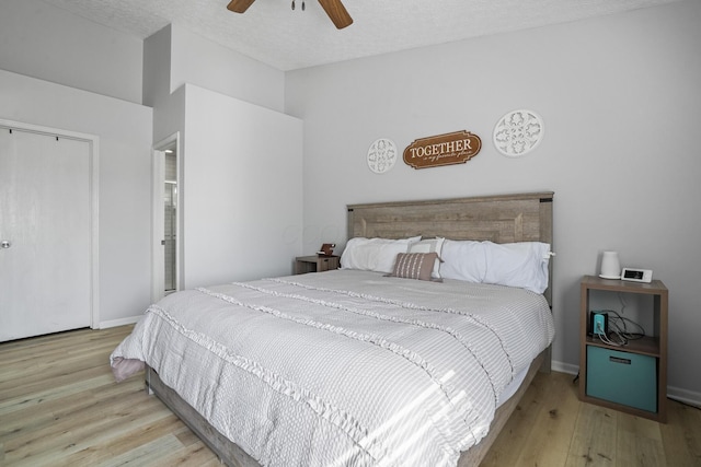 bedroom with a closet, baseboards, a ceiling fan, a textured ceiling, and wood finished floors