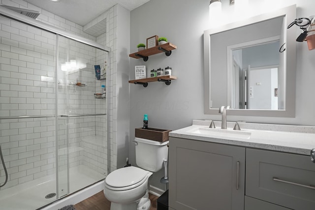 bathroom featuring toilet, a shower stall, and vanity