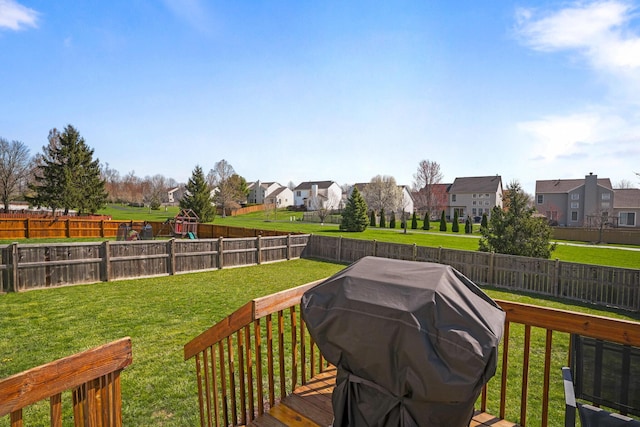deck with grilling area, a fenced backyard, a residential view, and a lawn