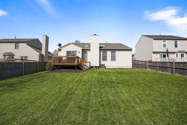 back of house featuring a yard, a deck, and a fenced backyard
