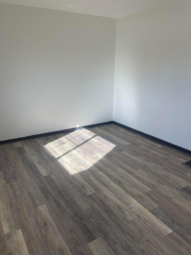 unfurnished room with visible vents, baseboards, and wood finished floors