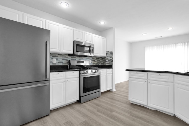 4899 Common Market Pl, Dublin, OH 43016 - kitchen featuring stainless steel appliances, dark countertops, decorative backsplash, light wood-type flooring, and white cabinets