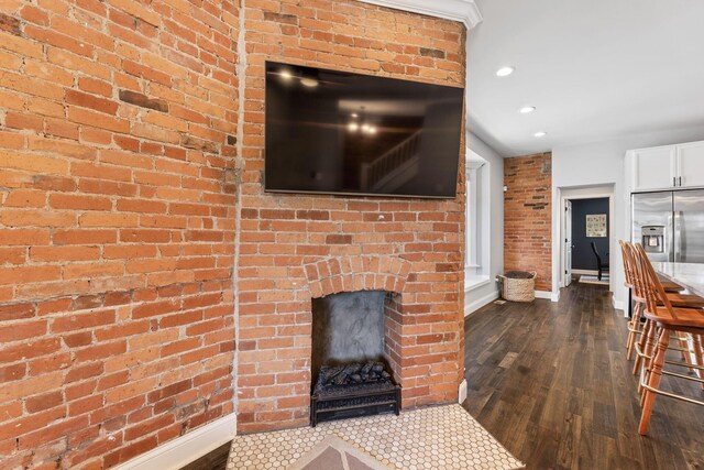 living area with recessed lighting, brick wall, a fireplace, dark wood-type flooring, and baseboards
