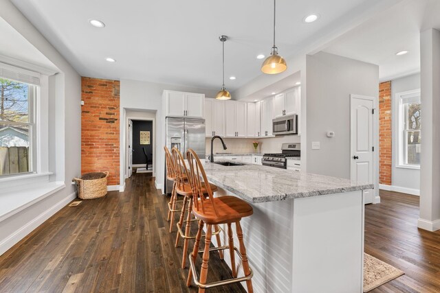kitchen featuring a sink, baseboards, appliances with stainless steel finishes, and a healthy amount of sunlight