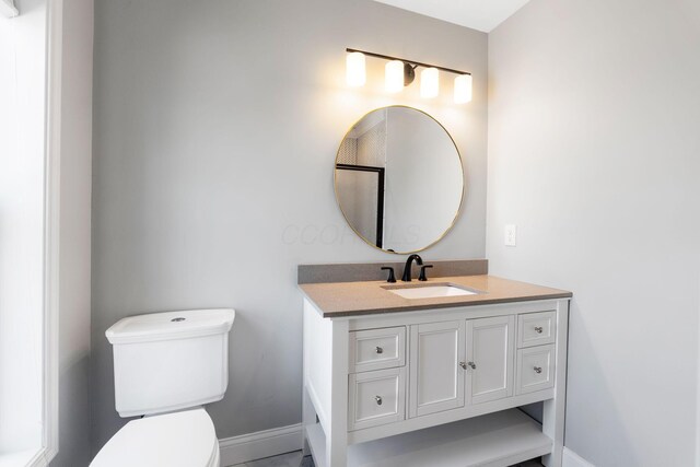 bathroom with toilet, vanity, and baseboards