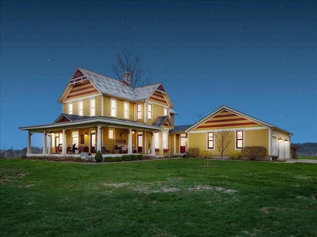 rear view of house with a porch, a lawn, a chimney, and an attached garage