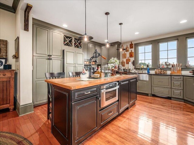 kitchen with oven, a sink, light wood-type flooring, butcher block countertops, and a kitchen island