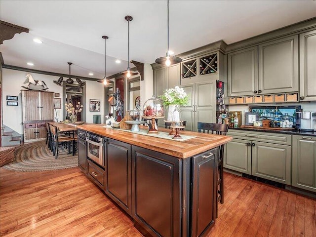 kitchen with a center island, stainless steel oven, pendant lighting, butcher block counters, and light wood-style flooring