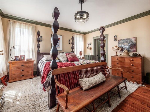bedroom featuring crown molding, wood finished floors, and multiple windows