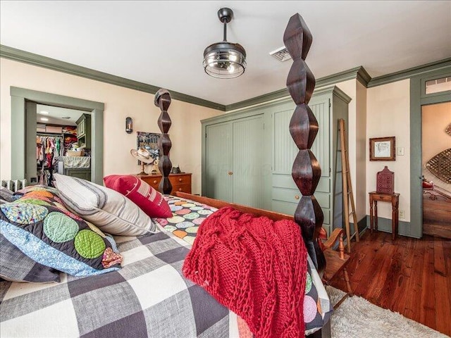 bedroom featuring dark wood finished floors, crown molding, visible vents, and a closet