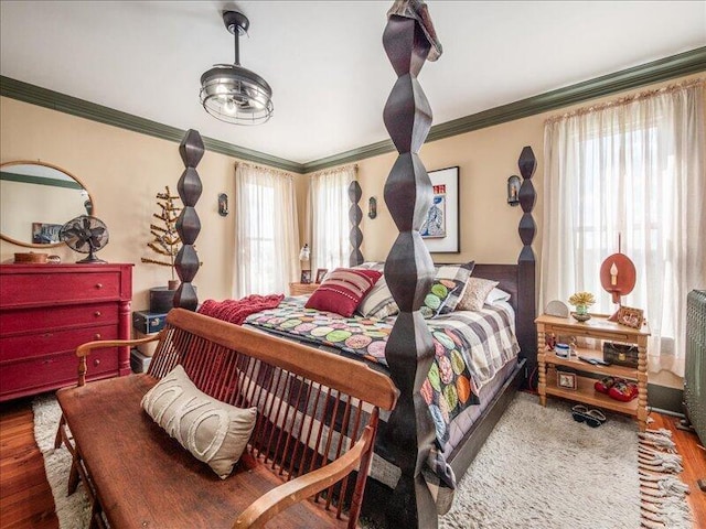 bedroom with wood finished floors and ornamental molding