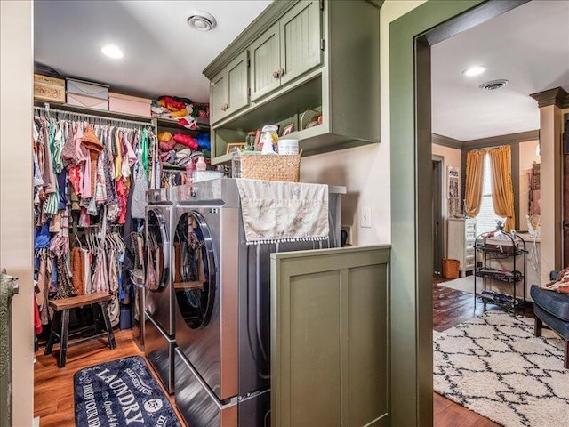 laundry room featuring separate washer and dryer, cabinet space, wood finished floors, and visible vents