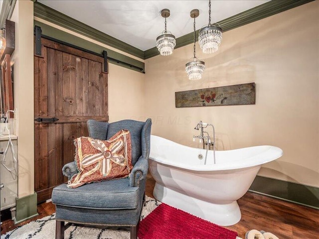 living area with a barn door, crown molding, and wood finished floors