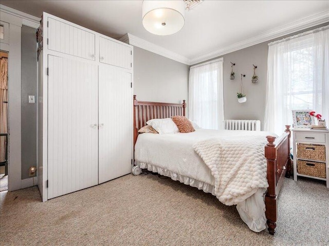 bedroom with radiator heating unit, a closet, light colored carpet, and ornamental molding