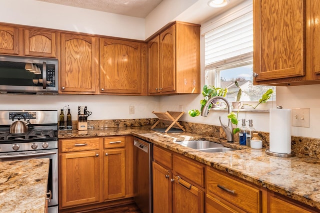 3073 Kola Way, Columbus, OH 43219 - kitchen featuring a sink, brown cabinetry, appliances with stainless steel finishes, and light stone countertops
