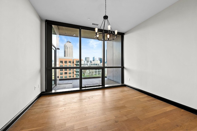 225 John H Mcconnell Blvd Unit 705, Columbus, OH 43215 - spare room featuring a city view, a notable chandelier, baseboards, a wall of windows, and wood finished floors