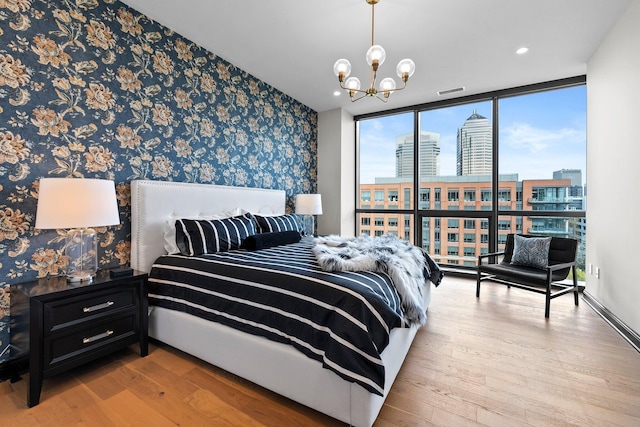 225 John H Mcconnell Blvd Unit 705, Columbus, OH 43215 - bedroom featuring a city view, floor to ceiling windows, wallpapered walls, a notable chandelier, and hardwood / wood-style flooring
