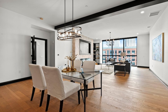 225 John H Mcconnell Blvd Unit 705, Columbus, OH 43215 - dining area featuring a notable chandelier, baseboards, visible vents, beam ceiling, and light wood finished floors