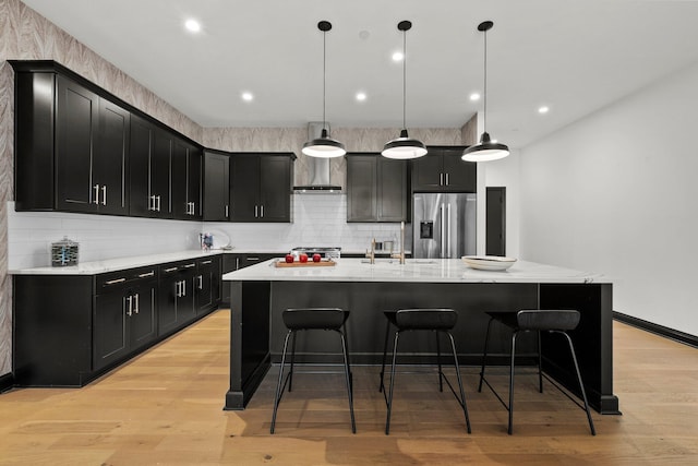 225 John H Mcconnell Blvd Unit 705, Columbus, OH 43215 - kitchen with a breakfast bar, a kitchen island with sink, high end refrigerator, dark cabinetry, and backsplash