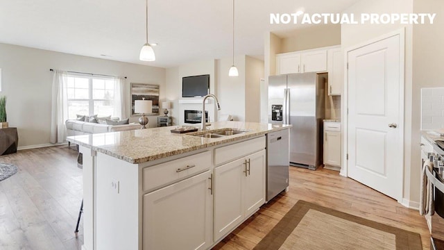 kitchen featuring light wood-type flooring, appliances with stainless steel finishes, a sink, and white cabinetry