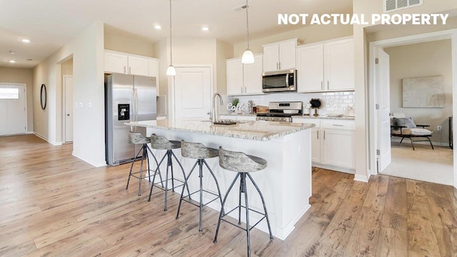 kitchen featuring backsplash, a breakfast bar, light wood-style floors, and stainless steel appliances